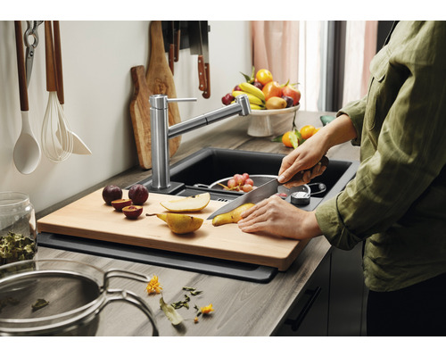 Keukenscène met spoelbak, kraan, snijplank en persoon die fruit snijdt