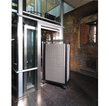 Een lift met een wagen vol platen in een gebouw.