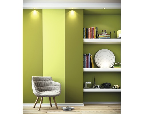 Lichte kamer met fauteuil, rek en groene wanddecoratie