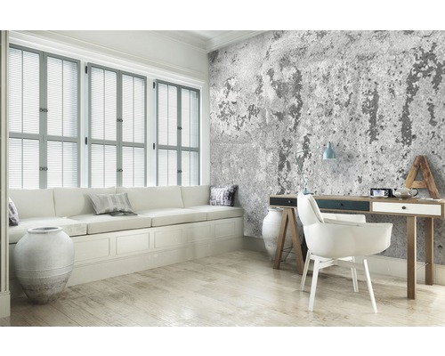 Woonkamer met raam, bank, bureau en betonnen wandbekleding