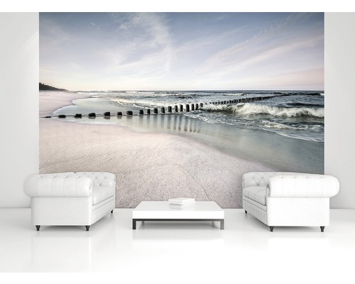 Woonkamer met fotobehang dat een strand met golfbrekers toont