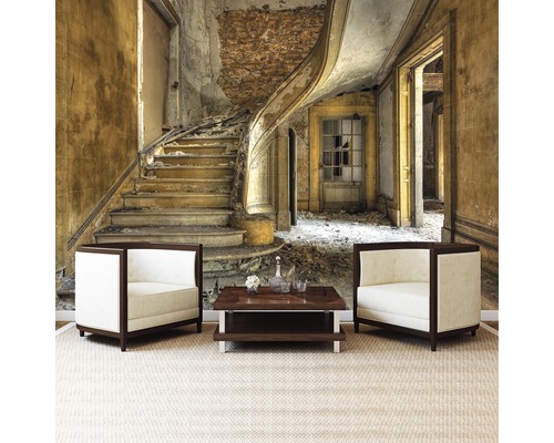 Wandafbeelding met trap in vervallen gebouw achter twee fauteuils en een tafel