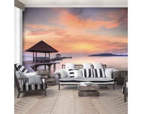 Woonkamer met fotobehang van een zonsondergang aan zee met houten steiger en paviljoen