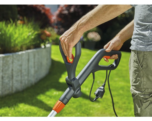 Close-up van een persoon die een grastrimmer met snoer bedient