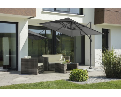 Tuinscène met zweefparasol, rotan zitgroep en terras voor een woonhuis