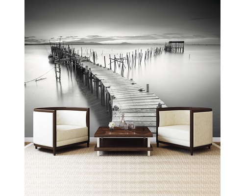 Woonkamer met fotobehang van een pier, twee fauteuils en een salontafel