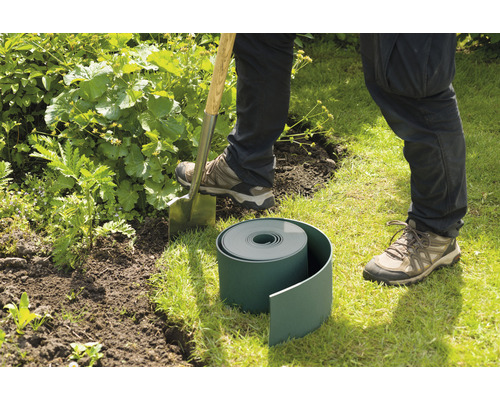 Persoon steekt gazonrand af met een spade in de tuin.