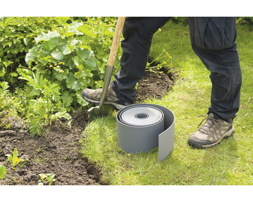 Een persoon graaft met een spade een gat voor een gazonrand