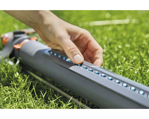 Een persoon stelt de sproeiers van een gazonsproeier in.