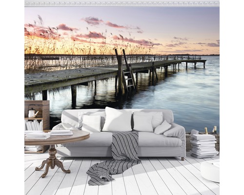 Woonkamer met fotobehang met een steiger aan een meer bij zonsondergang.