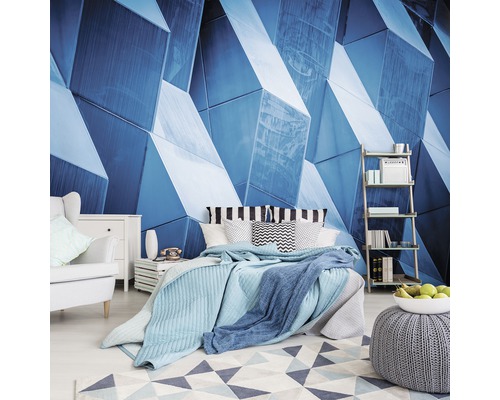 Slaapkamer met blauwe geometrische muurschildering, bed, fauteuil en plank