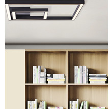 Moderne metalen plafondlamp in geometrisch design boven een boekenplank