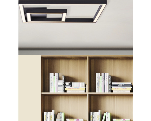 Moderne metalen plafondlamp in geometrisch design boven een boekenplank