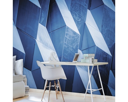 Woonkamer met geometrisch wandbehang, bureau en stoel.