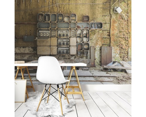 Woonkamer met fotobehang dat een oud schakelbord en een vervallen muur voorstelt, plus een wit bureau en een stoel.