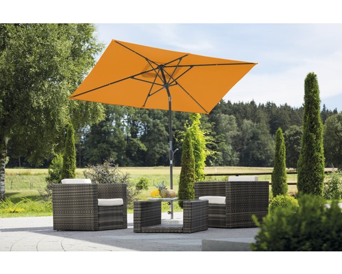 Tuinscene met rechthoekige parasol, rotan stoelen en tafel in de buitenlucht.