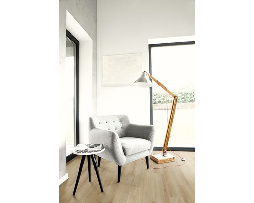 Lichte woonkamer met fauteuil, staande lamp en kleine tafel op houten vloer