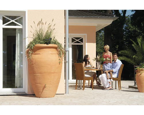 Tuinaanzicht met grote amfoor als regenopslag beplant naast terras met gezin