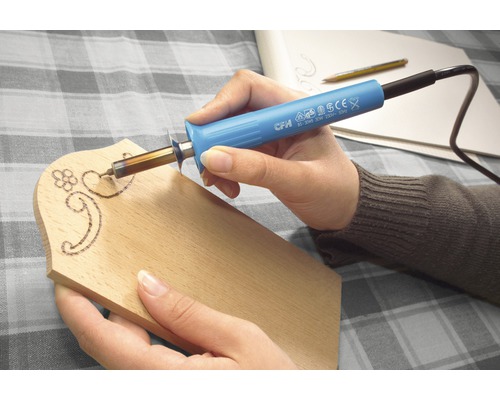 Persoon werkt met een pyrografiepen op een houten plank.