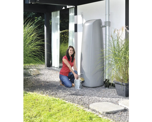Vrouw vult een gieter bij een regenwatertank in de tuin