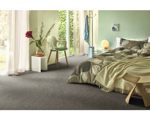 Moderne slaapkamer met grijs tapijt, bed met beddengoed met patroon en witte nachtkastjes.