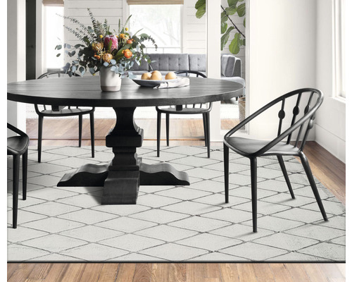 Een eetkamer met een ronde tafel, stoelen en een vloerkleed met patroon