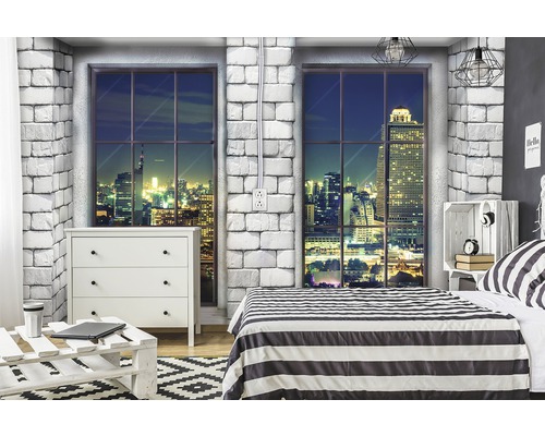 Slaapkamer met ladekast, bed en raam met uitzicht op de stad bij nacht