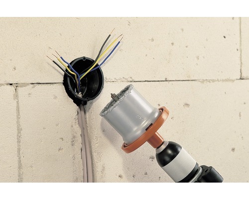 Boormachine met gatzaag boort gat in muur voor elektriciteitsleiding