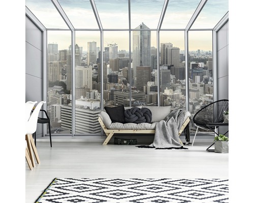 Lichte woonkamer met bank, tapijt en uitzicht op een stad