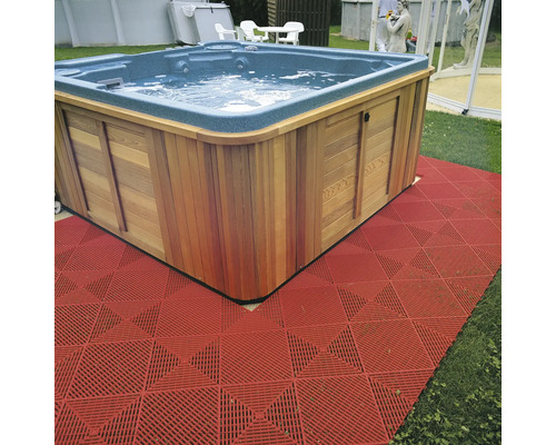 Vierkant bubbelbad met houten bekleding en rode vloerbedekking in de tuin.