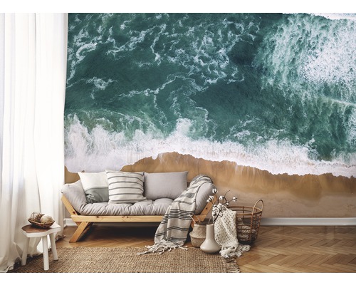 Woonkamer met fotobehang dat een kustlandschap met zee en zandstrand toont.