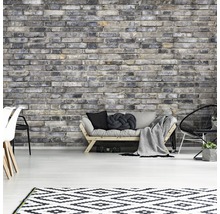 Woonkamer met grijze bakstenen muur, bank, vloerkleed en stoelen