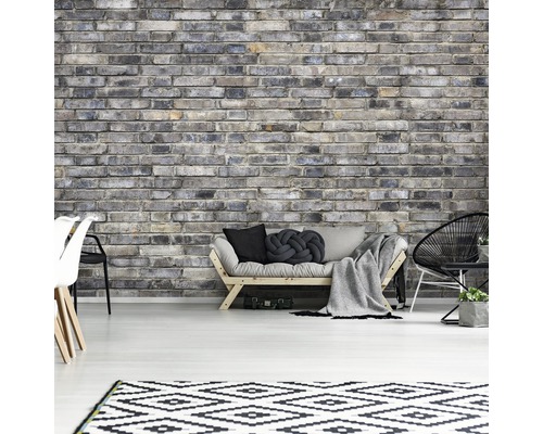 Woonkamer met grijze bakstenen muur, bank, vloerkleed en stoelen