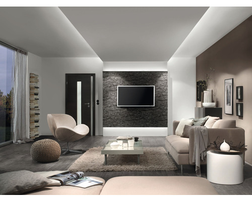 Woonkamer met bank, fauteuil, salontafel en televisie aan een stenen muur