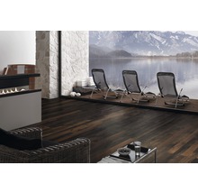 Interieur met donkere houten vloer, ligstoelen en uitzicht op een meer