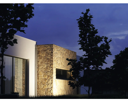 Buitenkant van een modern huis met stenen bekleding en ramen ''s nachts