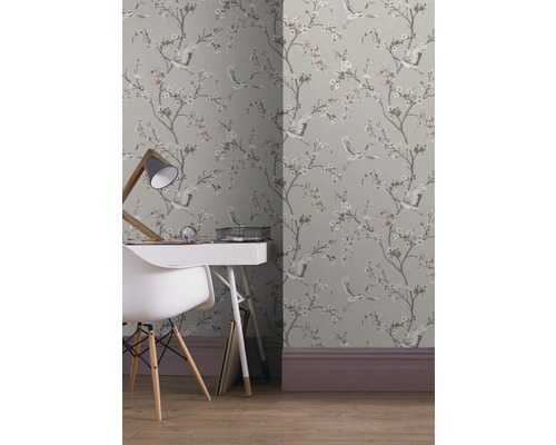 Kamer met behang met patroon van kraanvogels en bloesems, bureau en stoel.