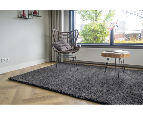 Grijs tapijt in de woonkamer met stoel en bijzettafel bij het raam.