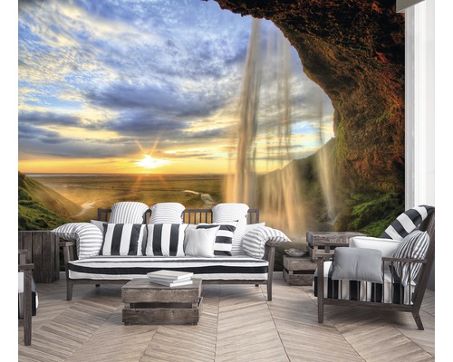 Woonkamer met fotobehang van een waterval en een landschap bij zonsondergang.