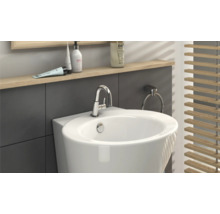 Detailaanzicht van een badkamer met een witte wastafel, kraan, handdoekring en houten jaloezie