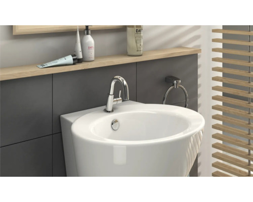 Detailaanzicht van een badkamer met een witte wastafel, kraan, handdoekring en houten jaloezie