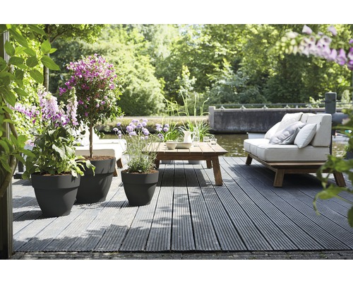 Terras met plantenbakken, houten tafel en bank bij het water