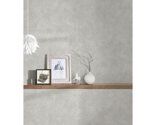 Woonkamer met grijs betonlook behang, gedecoreerd met een plank, lamp, foto''s en vaas