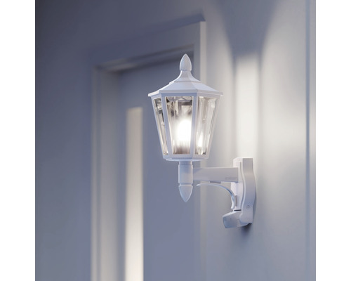 Witte lantaarn-stijl buitenwandlamp met bewegingssensor naast een deur