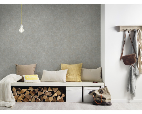 Woonkamer met grijs behang, zitbank, kussens en brandhout