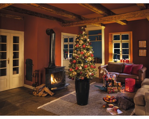 Kerstachtige woonkamer met open haard, bank en versierde kerstboom in plantenbak.