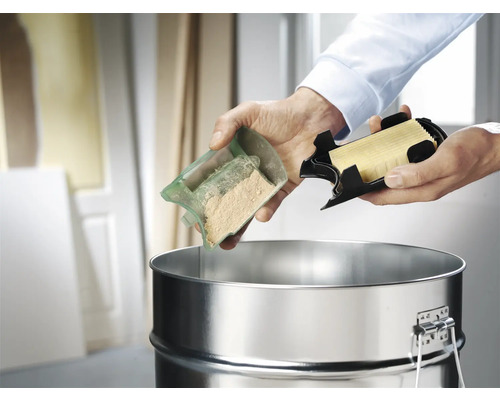 Een persoon leegt stof en een filter in een stofzuigerreservoir.