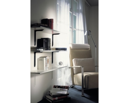 Woonkamer met boekenplank aan de muur en fauteuil naast een raam