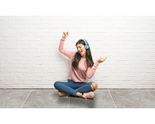 Jonge vrouw zit met koptelefoon op en luistert naar muziek