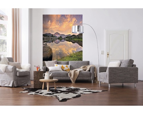 Woonkamer met bank, fauteuil, muurschildering met bergmeer en koeienhuidtapijt